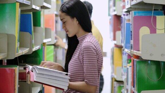 亚洲学生微笑着在图书馆看书大学生在图书馆看书