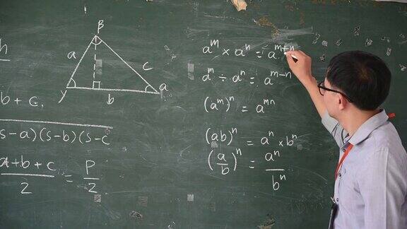 在课堂上男老师用白色粉笔在黑板上写字来教学生