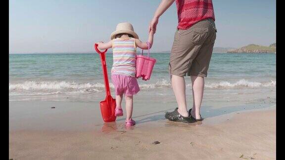 小女孩和妈妈在爱尔兰多尼戈尔的夏日海滩上玩耍