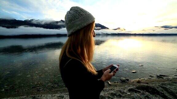 湖边的年轻女子在用智能手机