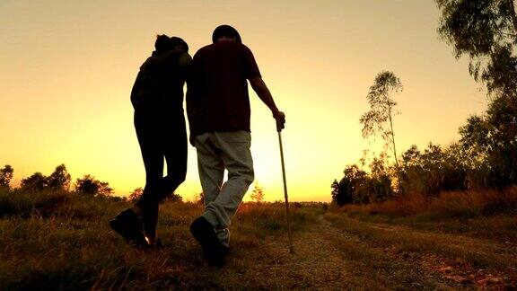 老人用手杖和他的女儿在夕阳下散步慢镜头