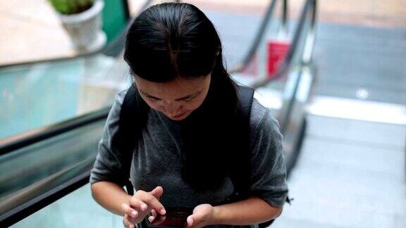女人在城市自动扶梯上使用智能手机