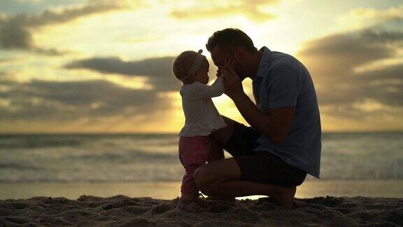 小女孩和她爸爸在海滩上散步的慢镜头