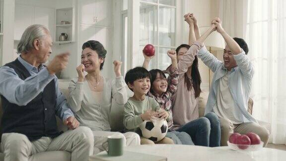 三代亚洲家庭在家里看电视直播的足球比赛