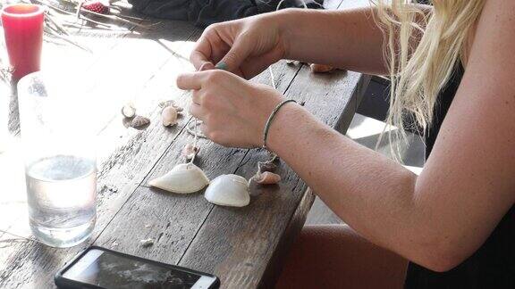 年轻女子用沙滩贝壳制作风铃