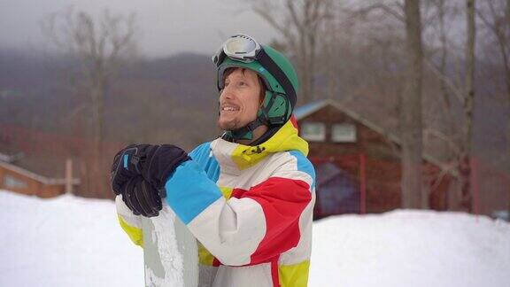 一个年轻人的特写镜头戴着头盔与滑雪板在一个山区度假胜地寒假SLowmotion拍摄