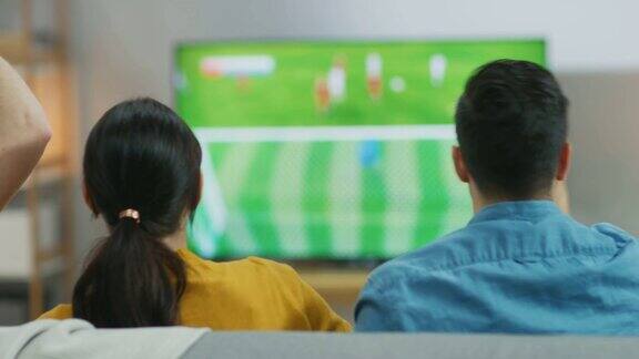 在家里各种各样的体育迷坐在沙发上看电视上重要的足球比赛他们为球队欢呼庆祝胜利后球队进球致胜移动拍摄