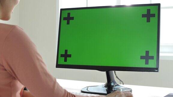 一位女士在用绿色屏幕的电脑