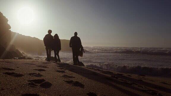 日落时分一群朋友在海滩上剪影散步