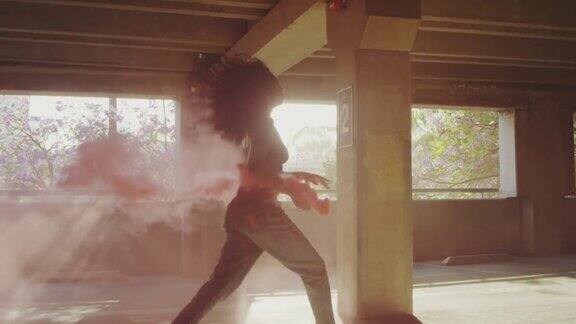 一名年轻女子的剪影与五颜六色的红色烟雾弹在停车场跳舞