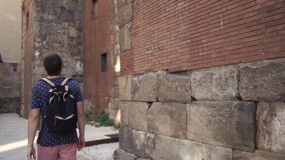 夏日里一个年轻人正沿着古老的中世纪建筑墙走着