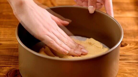 女用手把生面团均匀地放在烤盘里烘烤用具在后面