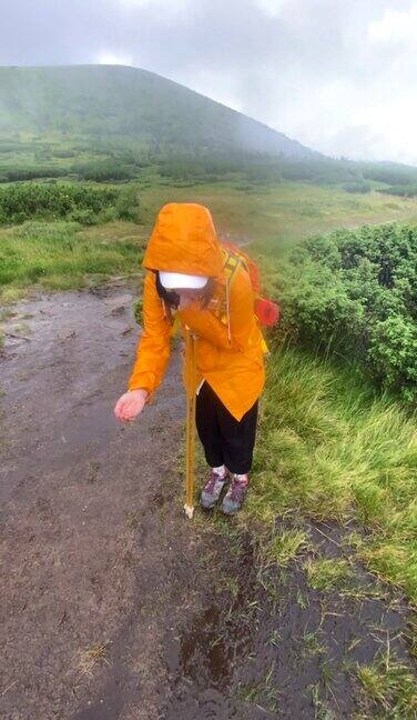 穿着黄色雨衣的女人在雨天沿着岩石小道走