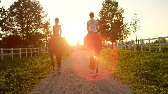 慢镜头:两个女朋友在夕阳下骑着棕色的马