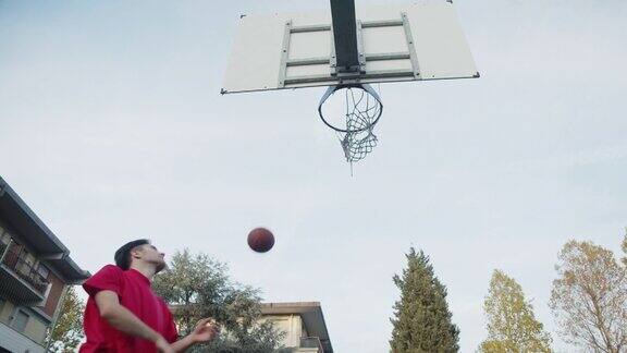 一个年轻的成年男子在篮球场上得分的低角度视角