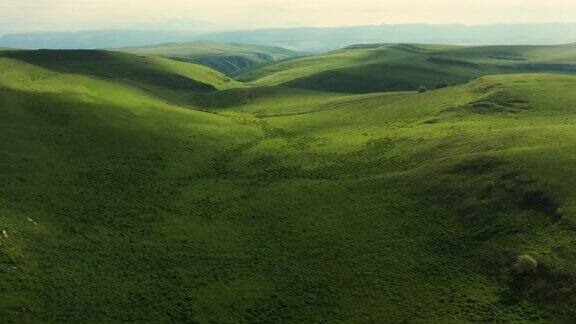 从山顶上可以看到穿过山丘的山路无人机拍摄的绿色山丘