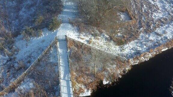 从空中俯瞰一座木桥穿过一条小河在一个霜雪过后的早晨加入一条小径