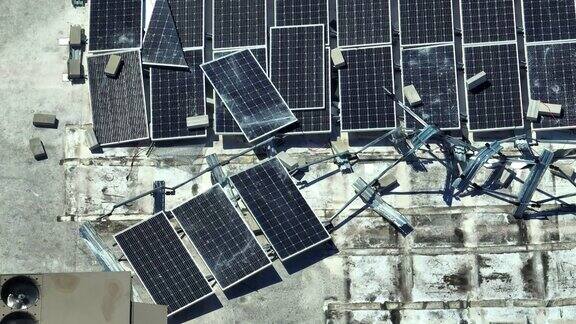 被飓风“伊恩”摧毁的破碎光伏太阳能电池板安装在工业建筑屋顶上用于生产绿色生态电力自然灾害的后果
