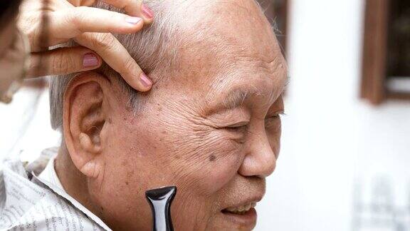 微笑的亚洲老人正在修剪头发