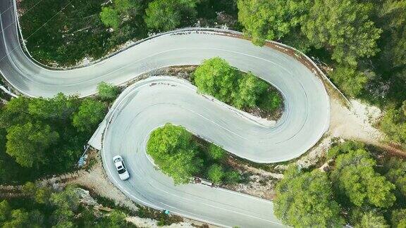 鸟瞰图视频的两个车道蜿蜒的道路在森林与一个自行车和一辆汽车