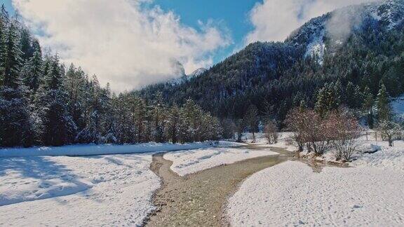 小河流在白雪皑皑的松树和山脉中流动