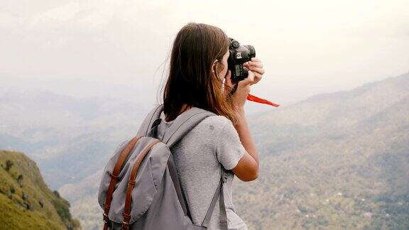 后视图年轻的女游客背着背包和相机在斯里兰卡拍摄史诗般的壮丽山景