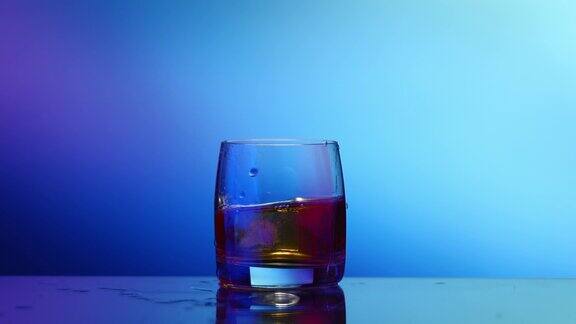 威士忌加冰用玻璃杯喷洒蓝色背景