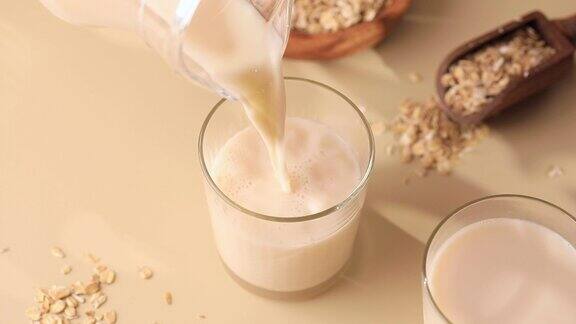 燕麦素牛奶从罐子里倒进玻璃杯里替代牛奶