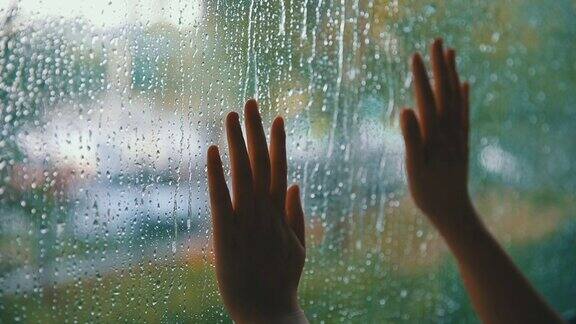 女人用手碰了碰窗户上的雨滴