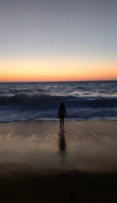 年轻女子跑向海边欣赏日落美景
