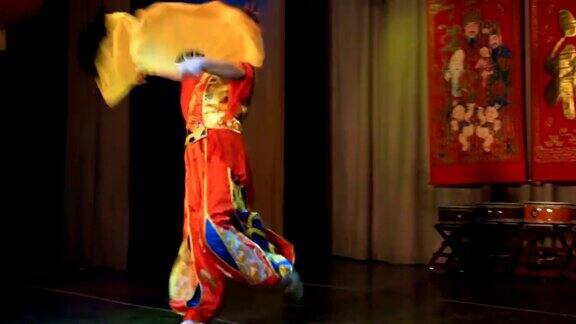 亚洲妇女穿着中国传统的红色服装拿着大大的黄色扇子跳舞