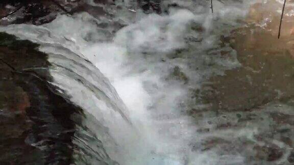 自然景观的小瀑布在一条小溪上隐藏在深山森林