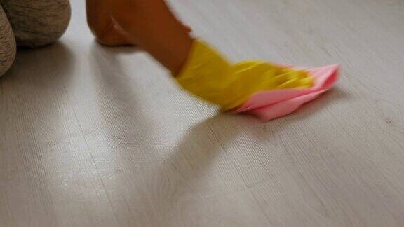 手戴橡胶手套用海绵和清洁剂清洁地板