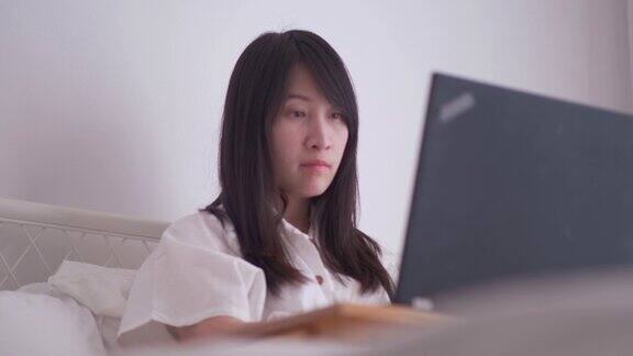 一名泰国妇女在卧室里用笔记本电脑工作