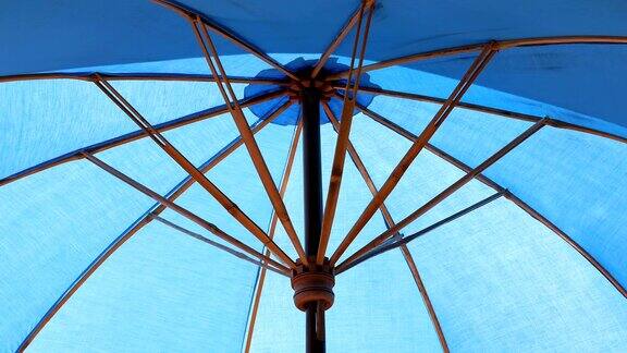 室外的蓝色遮阳伞在泳池的水面上反射阳光