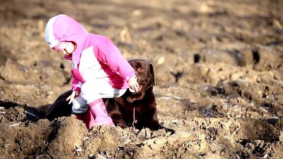 冬天小女孩和一只棕色拉布拉多寻回犬玩耍
