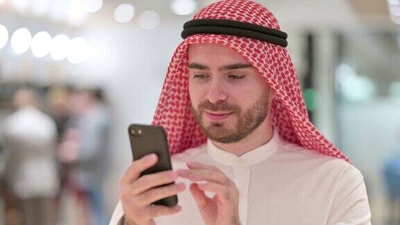 严肃的阿拉伯商人使用智能手机的肖像
