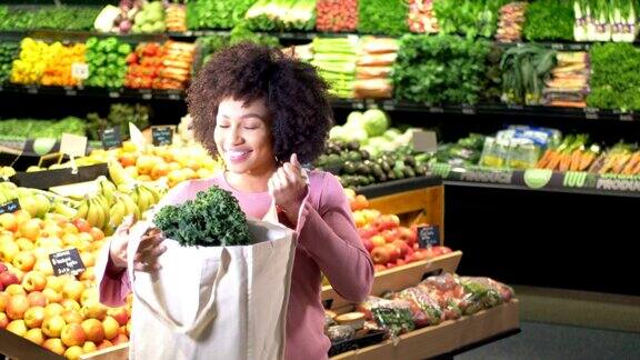 年轻的非洲裔美国人在超市里拿着可重复使用的袋子