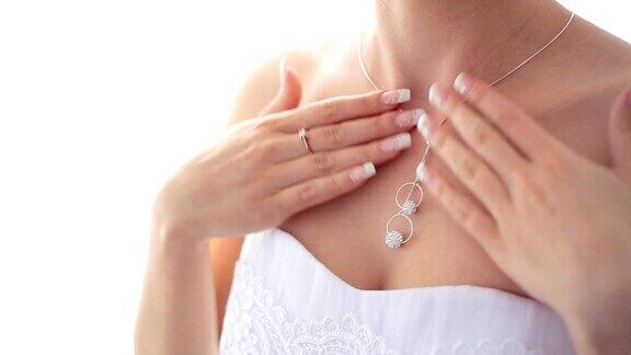 年轻女子穿着白色婚纱戴着闪亮的钻石吊坠