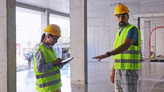 建筑工程师在工地上用写字板工作检查工作进度