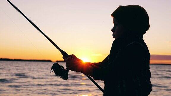 日落时分一个小孩在摆弄钓竿钓鱼
