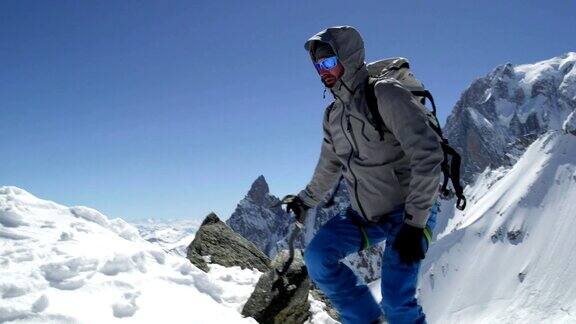 登山者用冰斧登上了白雪覆盖的山顶