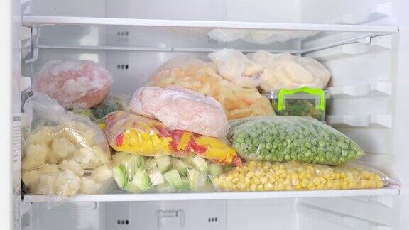 女手从冰箱里拿出冻肉冷冻水果蔬菜肉类在冰箱里