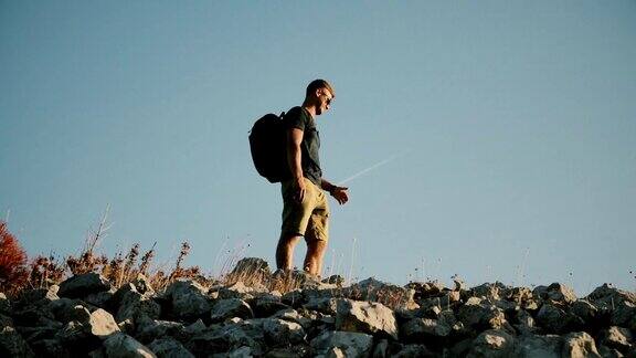 一个背着背包的男人在山上眺望远方健康积极的生活方式