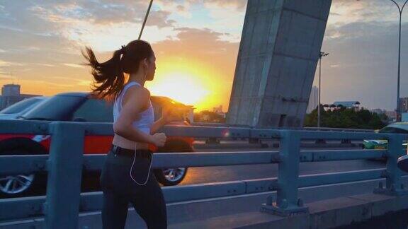 日落年轻女子慢跑过桥的慢镜头