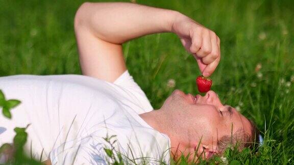 年轻人放松地躺在绿色的草地上吃浆果