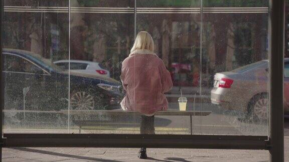 一个面目全非的年轻女子坐在公交车站等车