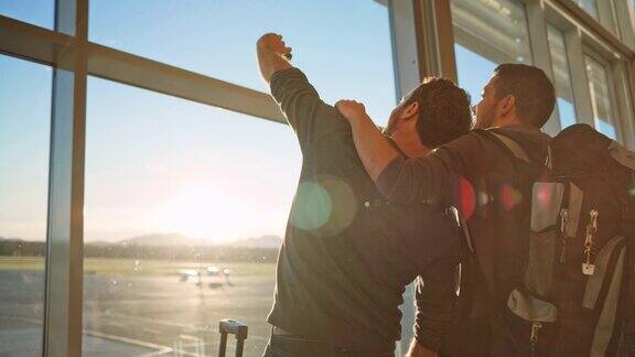 朋友们在阳光明媚的机场大楼的玻璃墙前自拍