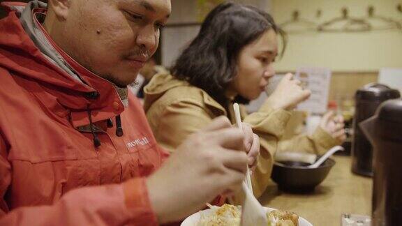 年轻的亚洲夫妇在餐厅吃拉面