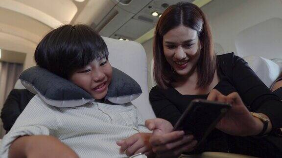 儿子和妈妈在飞机上玩手机游戏